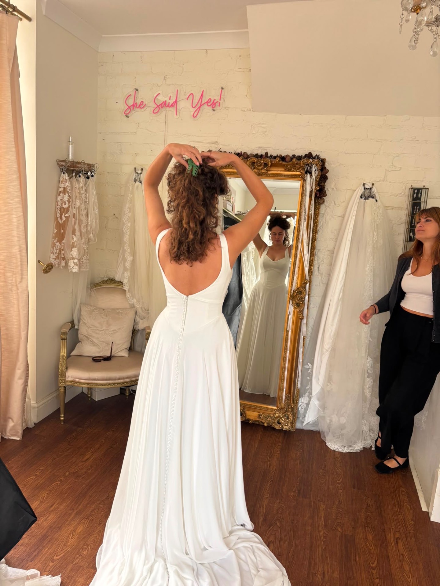 Bride admiring her dress in an ornate mirror during preparations
