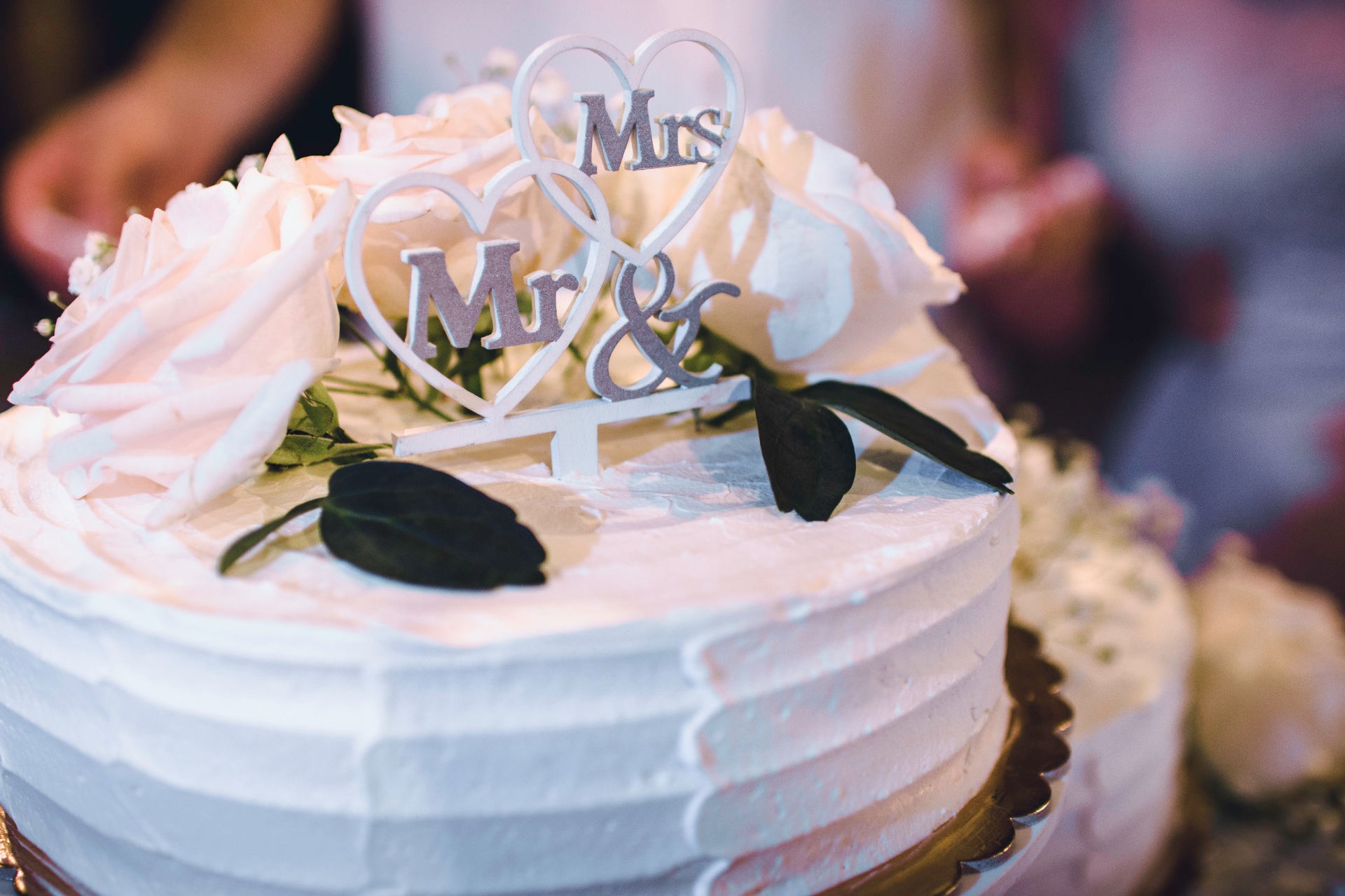 Ivory wedding cake topped with white roses and a Mr & Mrs heart topper