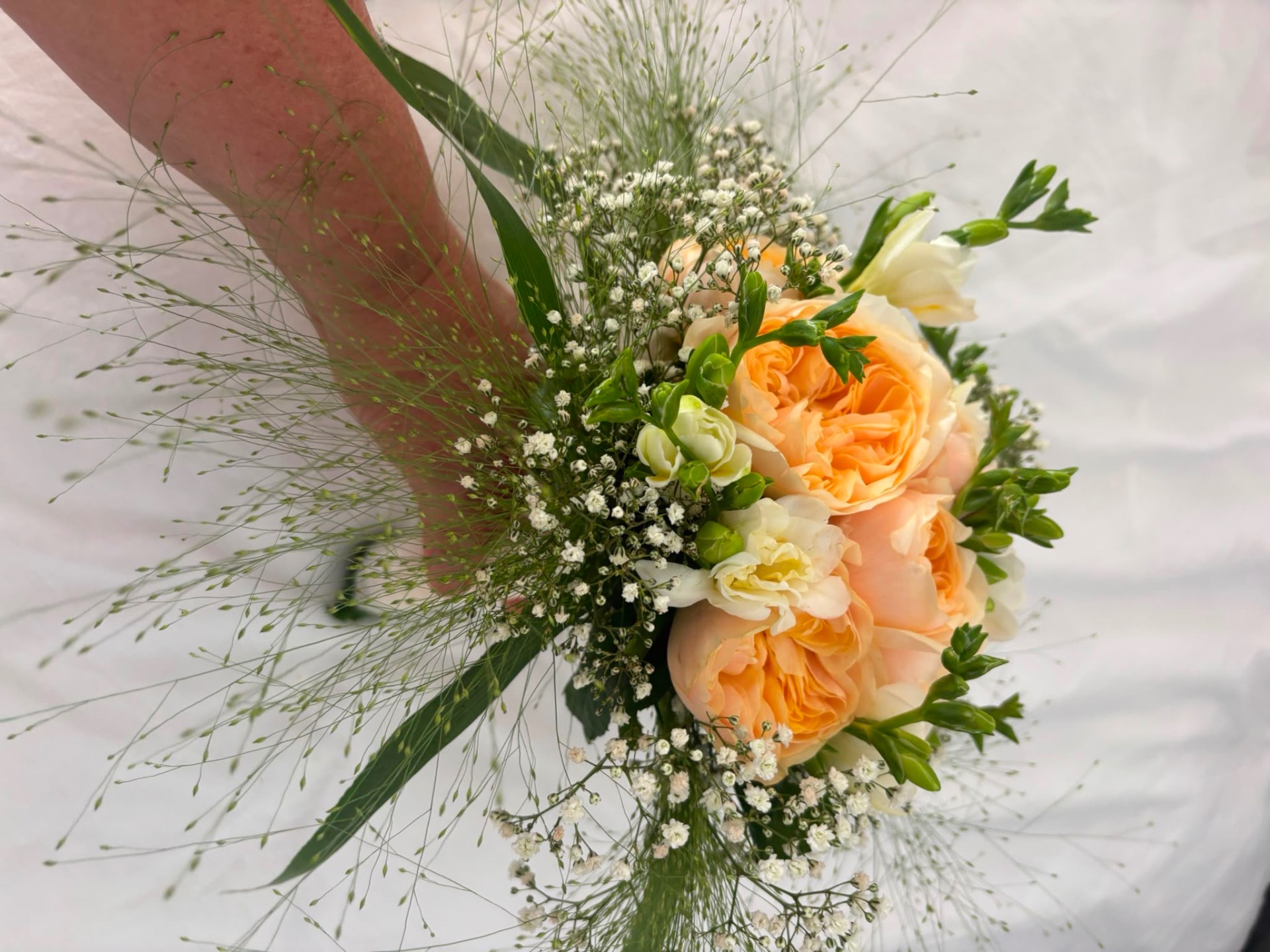 Bridal bouquet of peach garden roses, white freesias, and baby's breath with flowing grasses